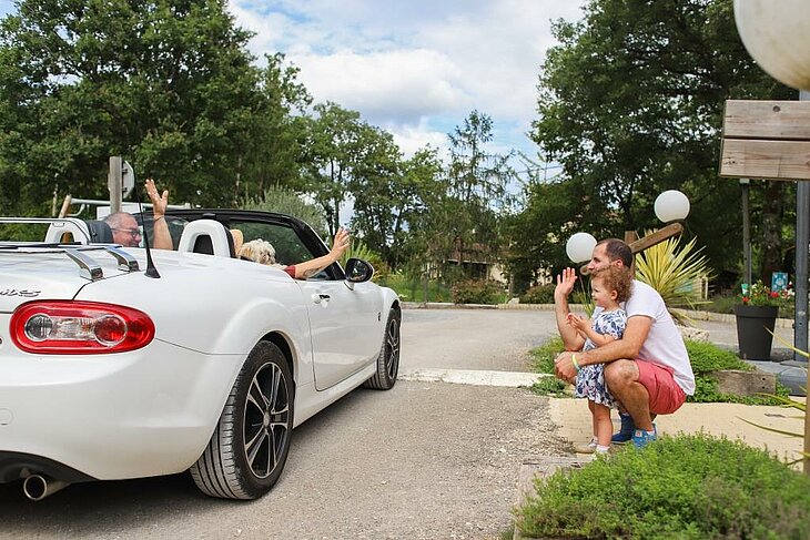 Famille et couple de seniors se saluant à la sortie d’un camping nature, symbole de la convivialité et du bien-être des vacances simples.