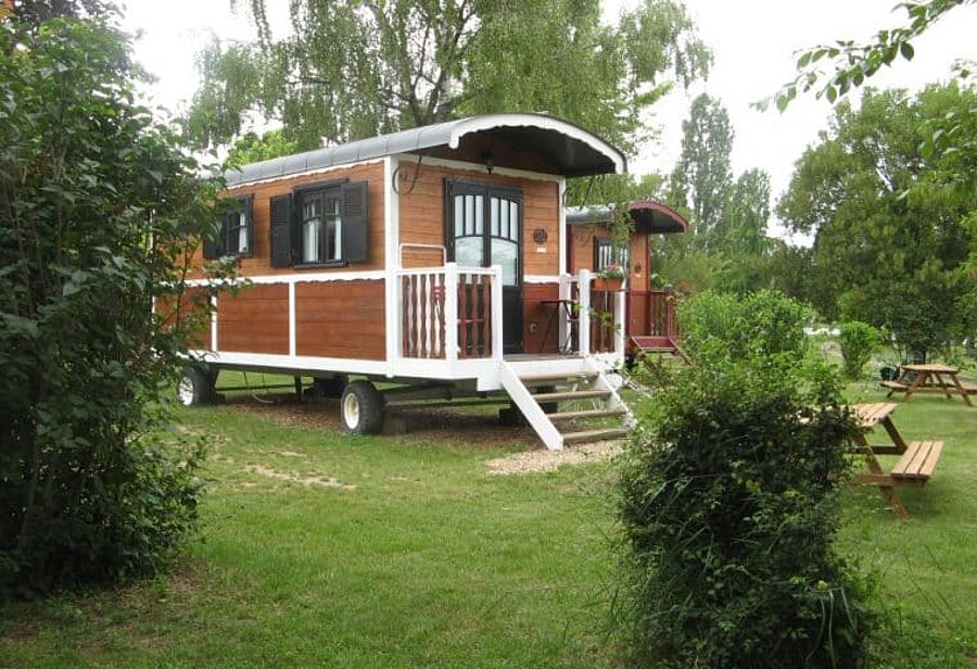 Roulottes en bois installées dans un cadre verdoyant, offrant un hébergement insolite et confortable pour des vacances en camping près de Gien, dans le Centre-Val de Loire.