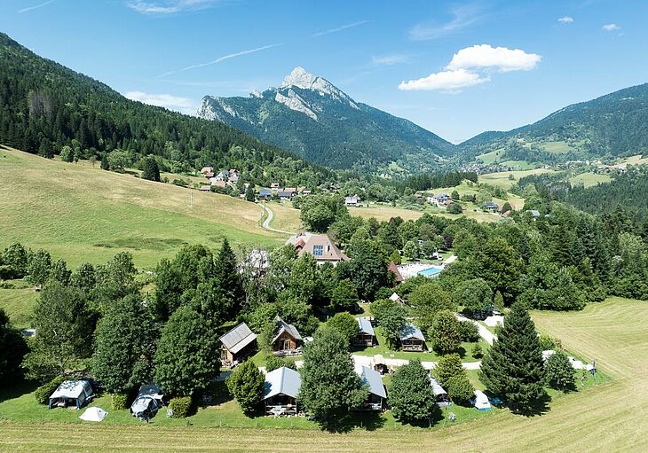 Camping nature à la montagne pour des vacances en famille Vue aérienne d’un camping nature à la montagne entouré de forêts et de vallées pour des vacances en famille.